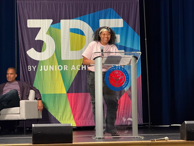 3DE student addresses the audience from a podium on a stage