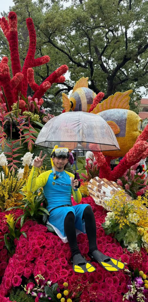 High School student is seated on the Rose parade float with an umbrella in hand